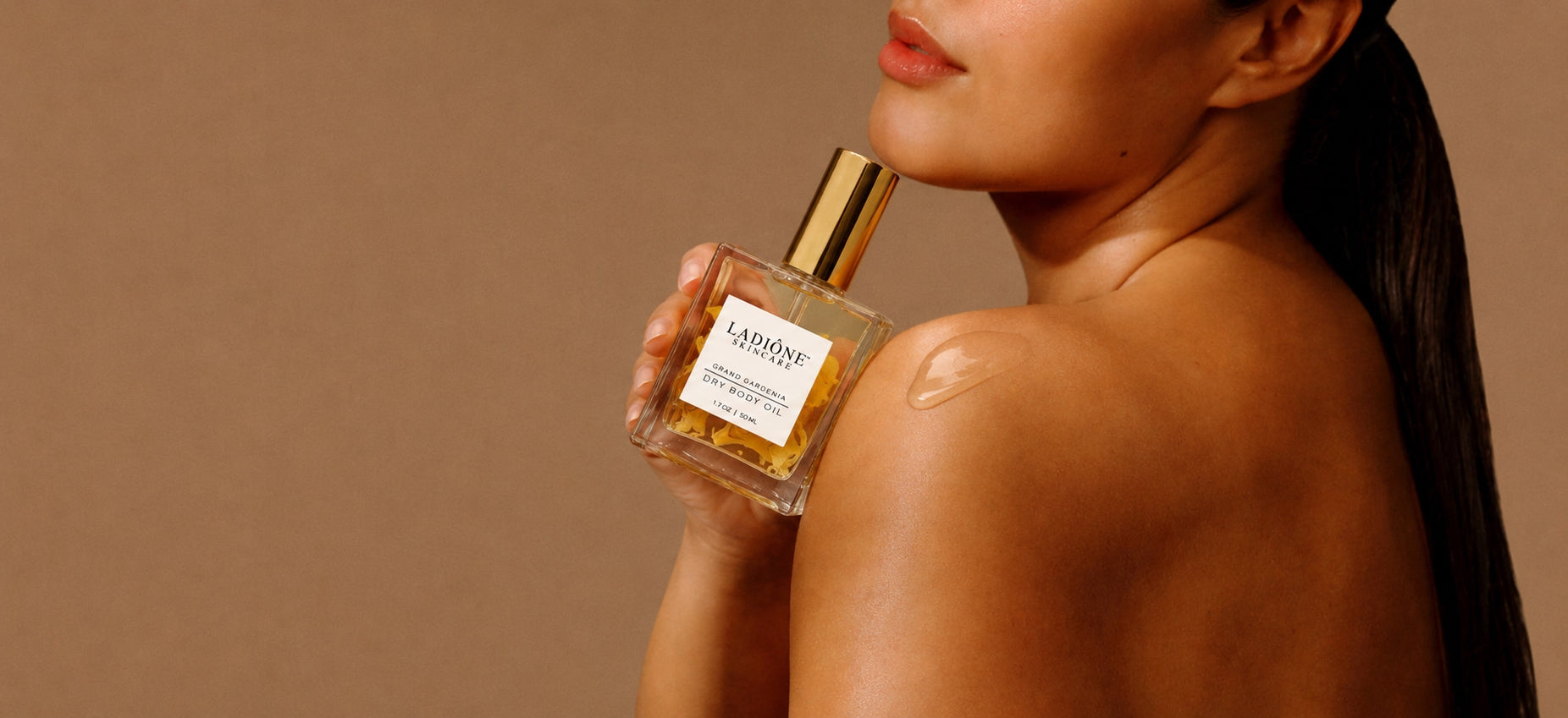 Woman holding a perfume bottle with a brown background