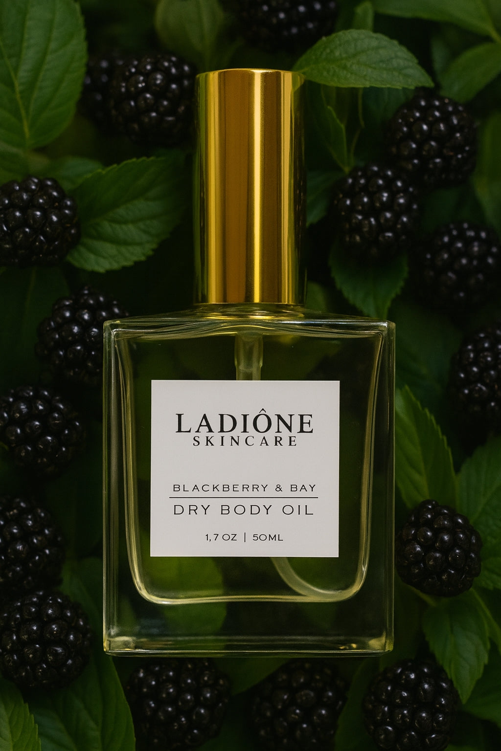 Ladióne Skincare dry body oil bottle with gold cap on a blackberry and leaf background