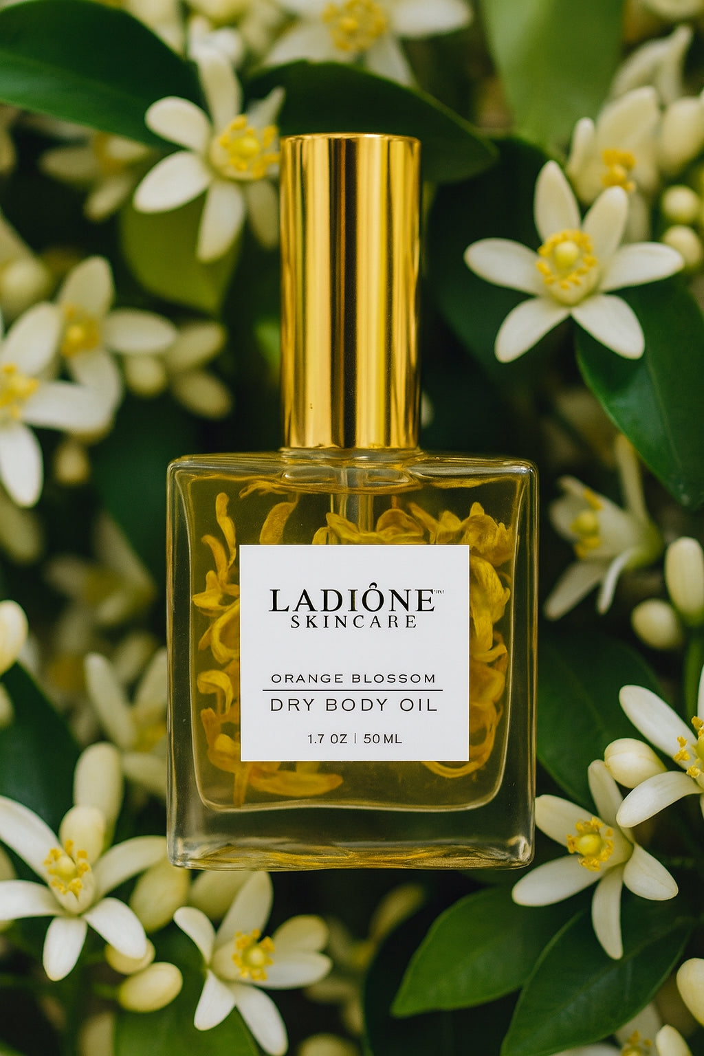 Ladione skincare dry body oil bottle with gold cap and label, surrounded by orange blossoms.